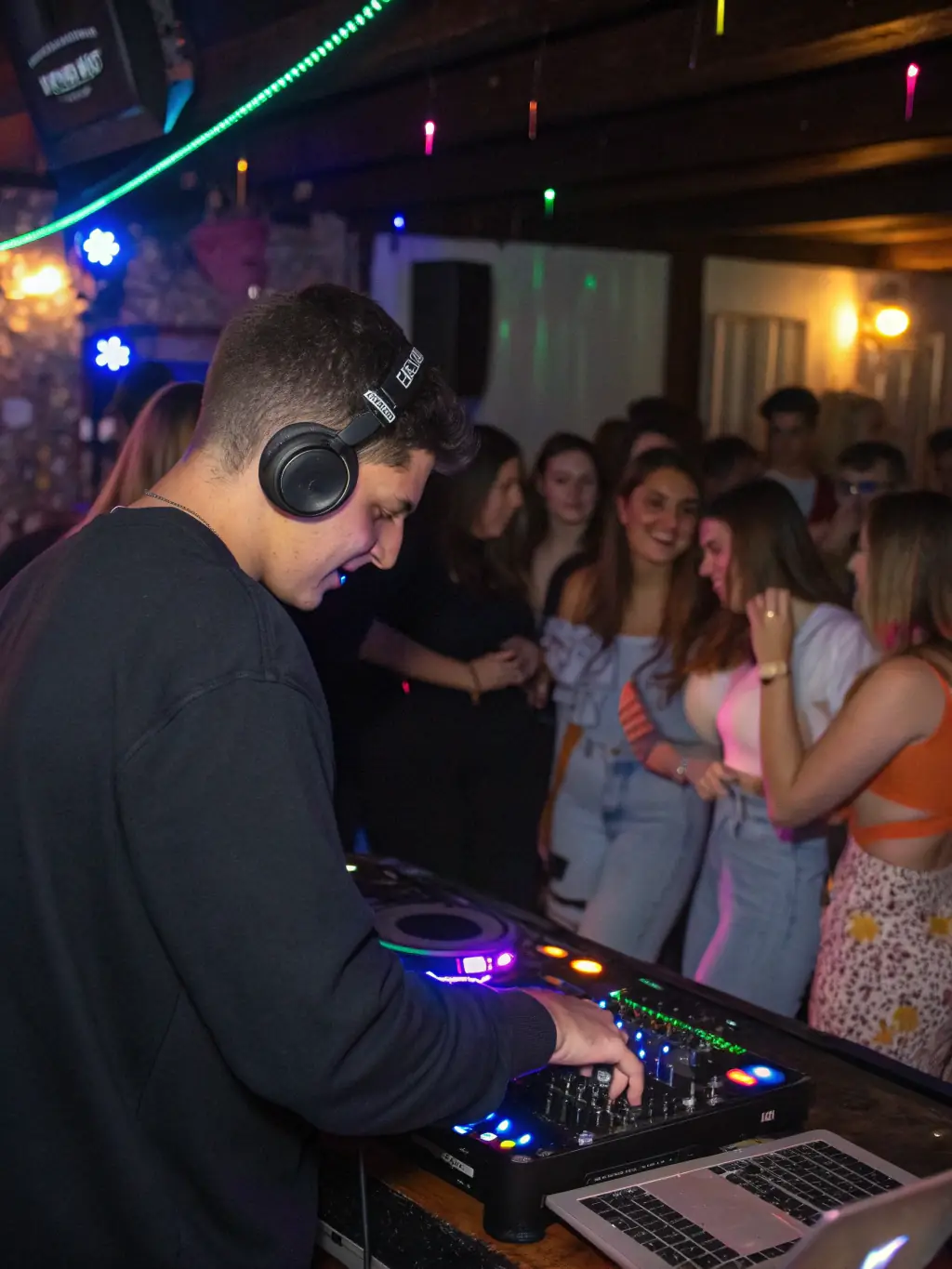 A vibrant photograph capturing the energy of a HAUS GANG electronic music event, featuring a DJ performing in front of a crowd with dynamic lighting.